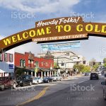 Golden, USA - May 17, 2014: Big sign 'Welcome to Golden' at Washington Avenue. The main street in old town of Golden, Colorado is popular among tourists and locals. There are people visible walking and cars parked on the sides of the street.